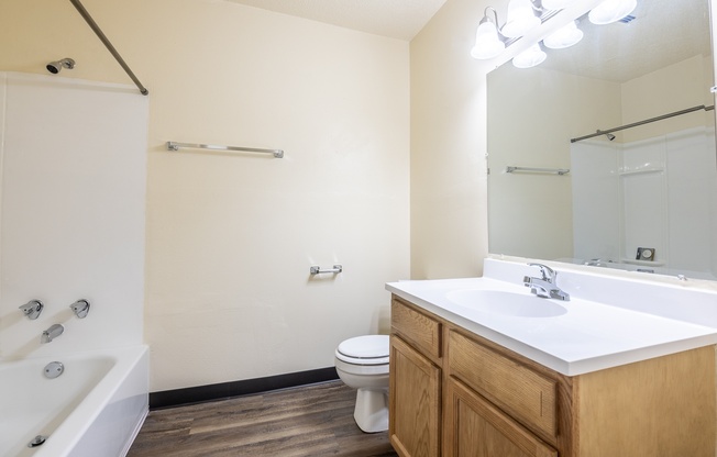 A white bathroom with wooden cabinets and a white sink.