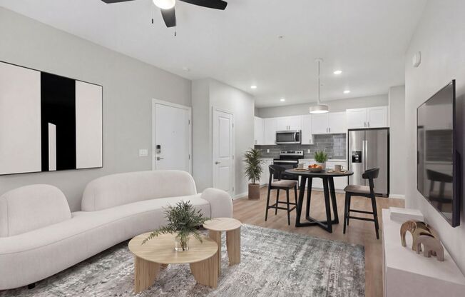 Contemporary open-plan living room and kitchen with sleek furniture, modern appliances, and elegant decor at Summit on Boulder Apartments in Henderson NV