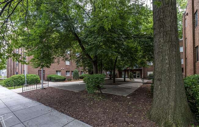 a sidewalk and trees in front of a brick building