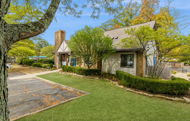 a small house with a driveway and lawn in front of it