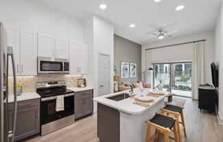 an open kitchen and living room with a large window and a table with chairs