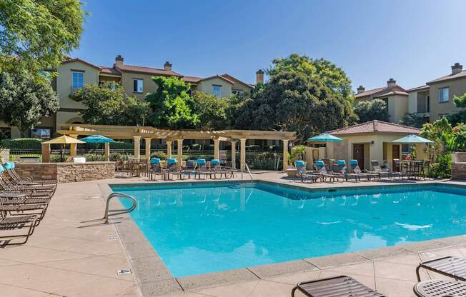 A large swimming pool surrounded by lounge chairs and umbrellas.