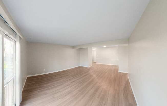an empty living room with wood flooring and a large window