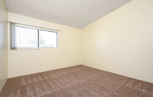 a bedroom with white walls and a window at Park Columbia Apts, Hemet, CA 92544