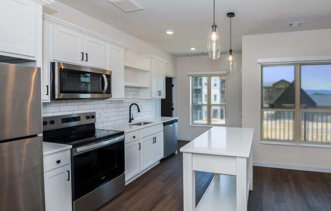 a kitchen with white cabinets and stainless steel appliances at The Crossings at Windsong, Prescott Valley, AZ