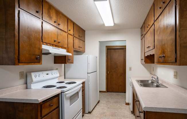 an empty kitchen with white appliances and wooden cabinets. Fargo, ND Hawn Apartments