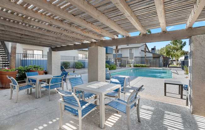 A patio with a table and chairs under a wooden pergola.