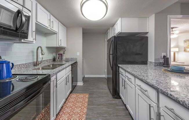 A kitchen with black appliances and white cabinets.