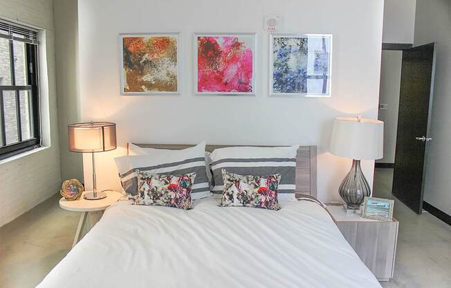 A bedroom with a large bed and two lamps.