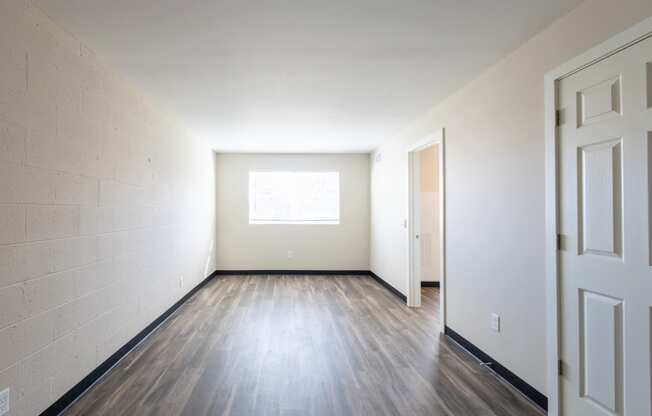 the living room of an empty house with wood floors and a window