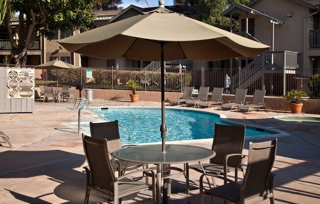 a swimming pool with a table and chairs under an umbrella