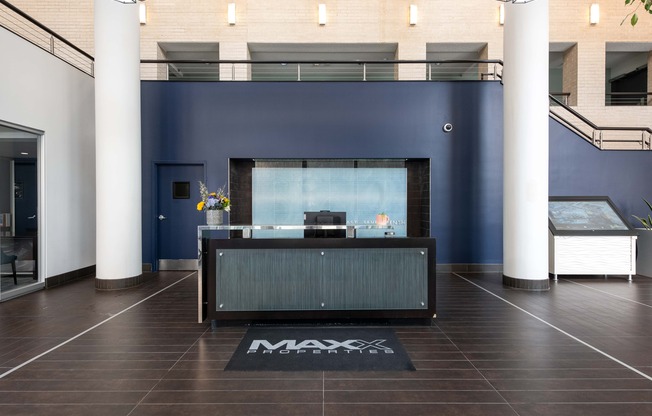 a reception desk in a lobby with a blue wall and white pillars