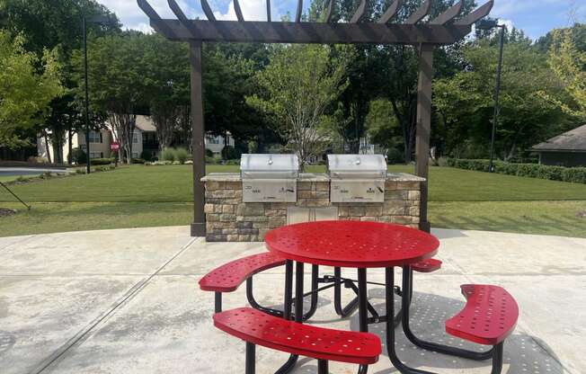 a picnic table and chairs in front of a grill