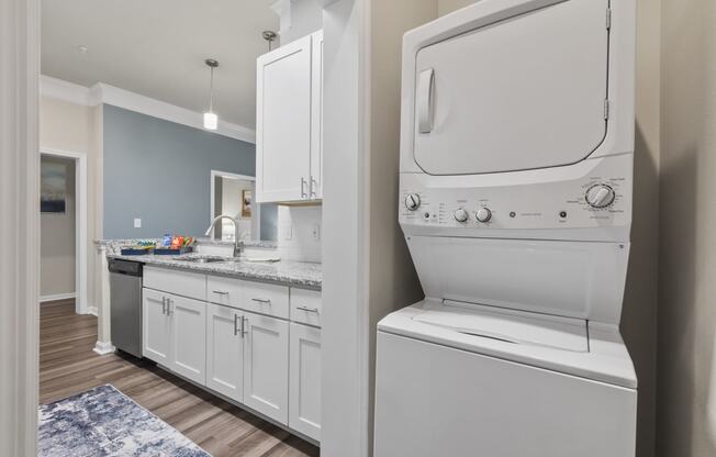 a laundry room with a washer and dryer and a kitchen with white cabinets