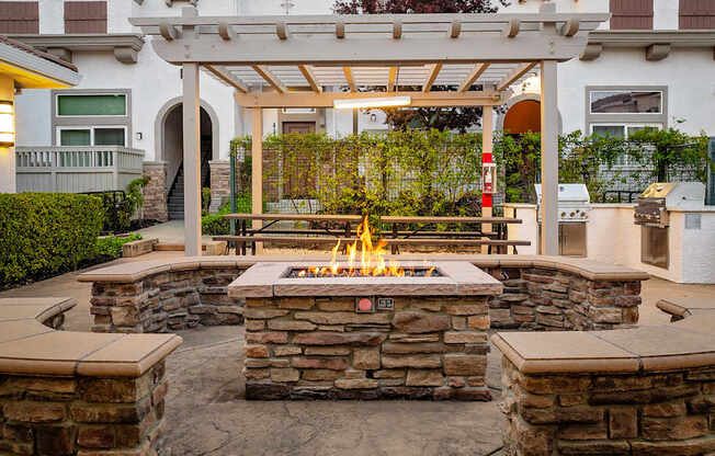 A patio with a fire pit and a pergola.