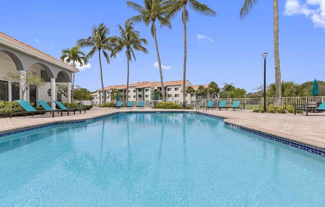 a large swimming pool with palm trees in front of a building