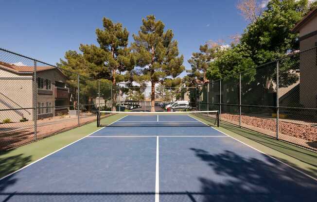 a tennis court with a fence around it and trees