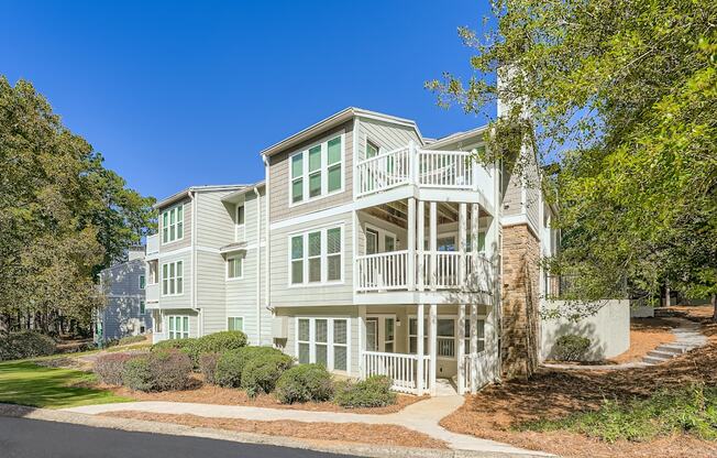 A large white house with a balcony and a tree in front.