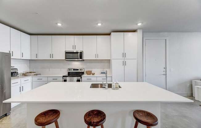 a kitchen with a white counter top and three stools