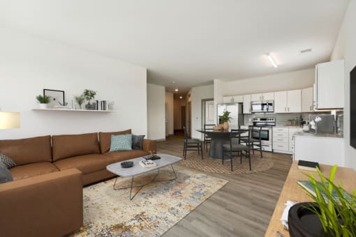 a living room with a couch a table and a chair and a kitchen in the background at The Waterford At Rocketts Landing Apartments, PRG Real Estate, Richmond, Virginia