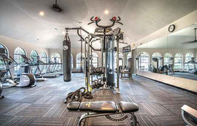 A gym with a variety of equipment including a punching bag, treadmill, and weight bench.