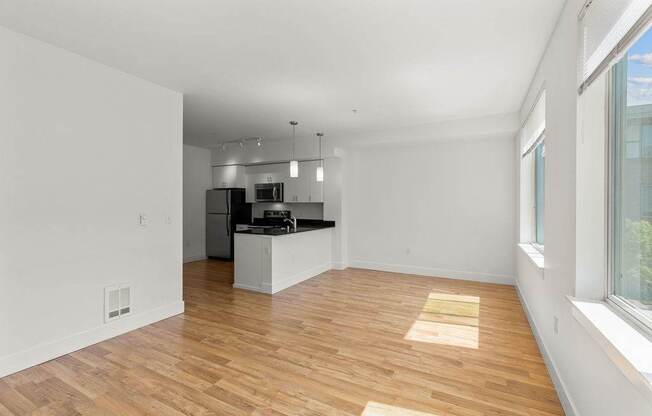 A kitchen with white walls and wooden floors.
