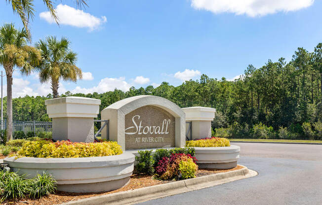 A sign that says Stovall at River City surrounded by plants and trees.