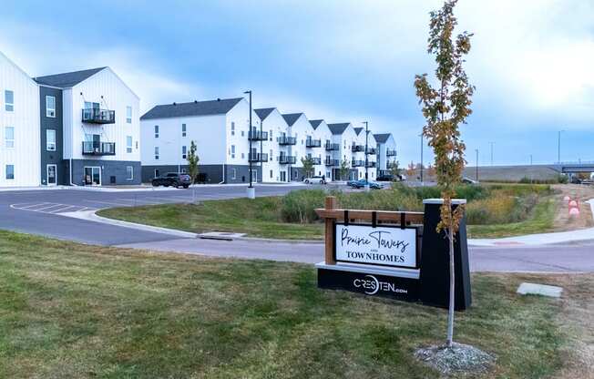 A sign for a development called "Pine Ridge Townhomes" is in front of a grassy area with apartment buildings in the background.