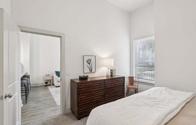 A bedroom with a bed, dresser, and chair.