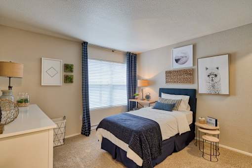 A bedroom with a bed, nightstand, and a desk.