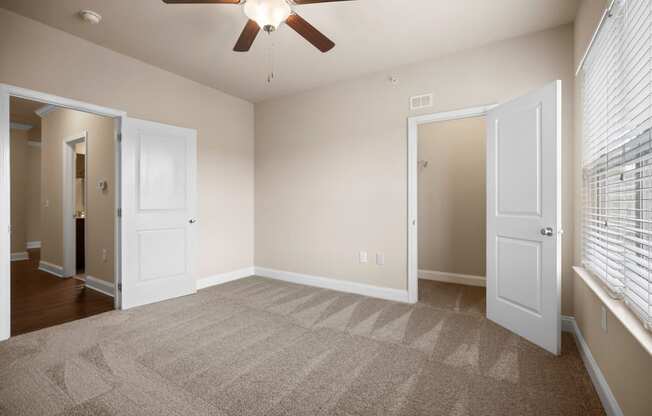 an empty living room with carpet and a ceiling fan