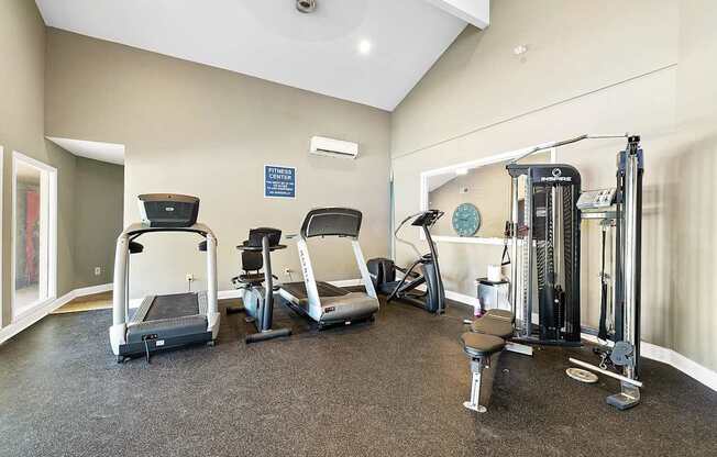 A gym with treadmills, elliptical machines, and weights.