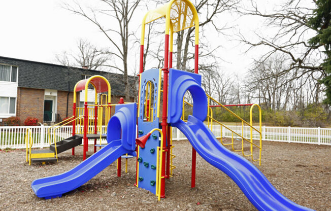 A playground with a blue slide and yellow and red structures.