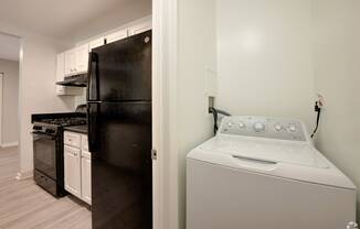 a white washer and dryer in a kitchen with a black refrigerator and