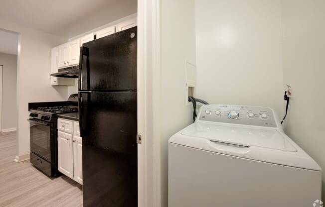 a white washer and dryer in a kitchen with a black refrigerator and