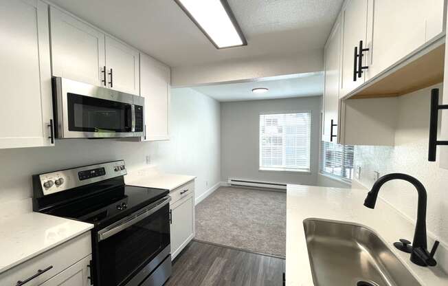 an empty kitchen with white cabinets and black appliances and a sink