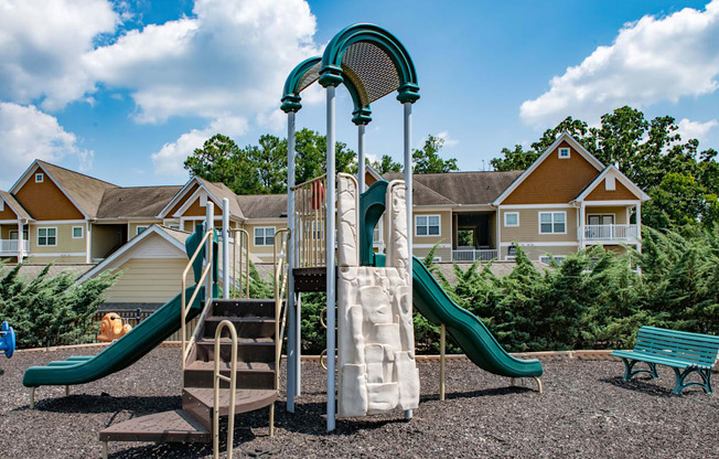 a playground with a slide and climbing equipment in front of a row of houses at Ashby at Ross Bridge, Hoover, Alabama