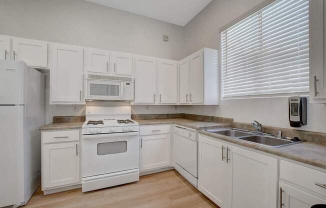 A kitchen with white appliances and cabinets.