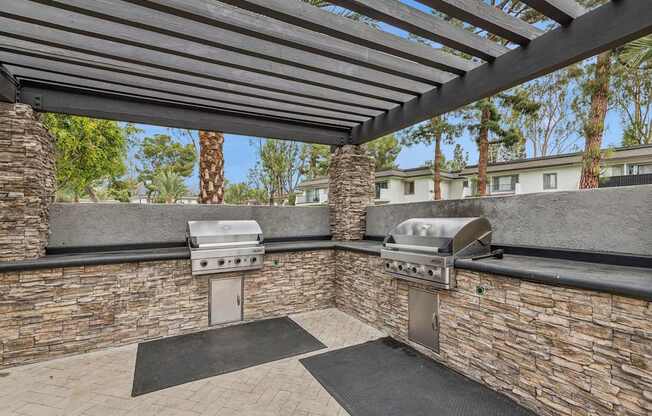 A patio with a grill and a stone wall.