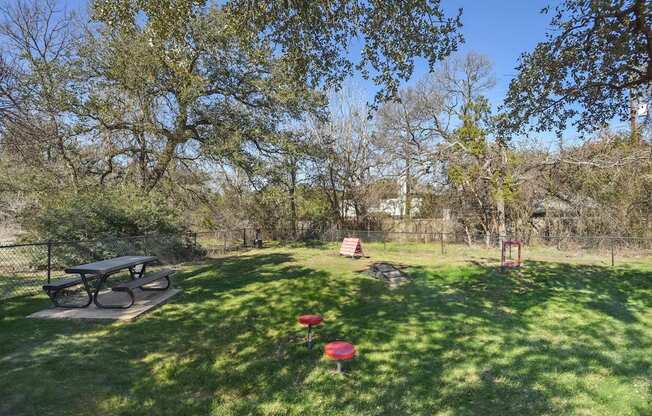 A park with a picnic table and a red object on the grass.