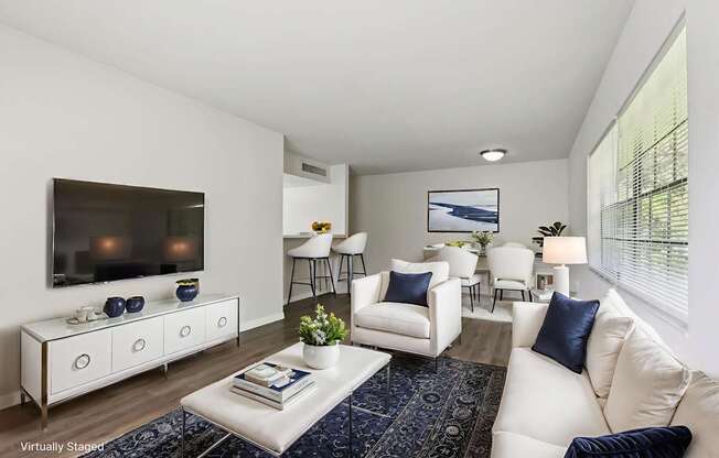 A living room with white furniture and a flat screen TV mounted on the wall.