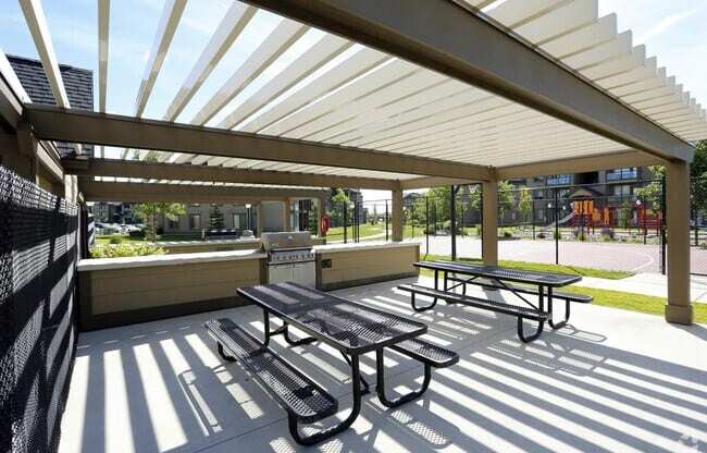 A picnic area with a grill and picnic table in front of a building