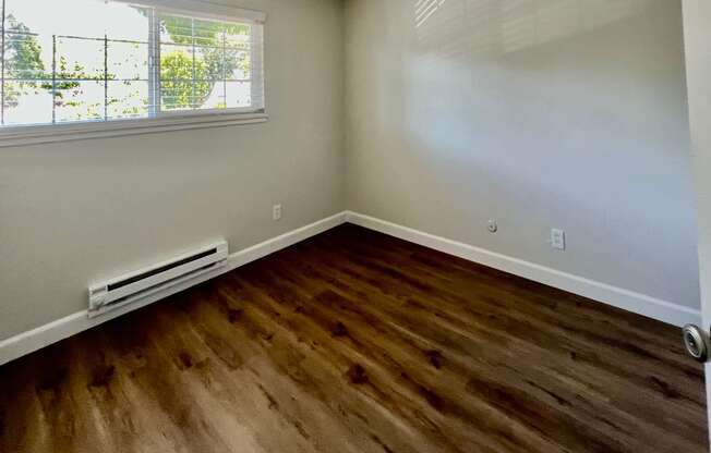 an empty room with wooden floors and a window