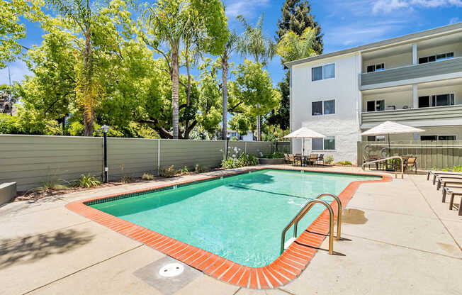 A swimming pool in a backyard with a building in the background.