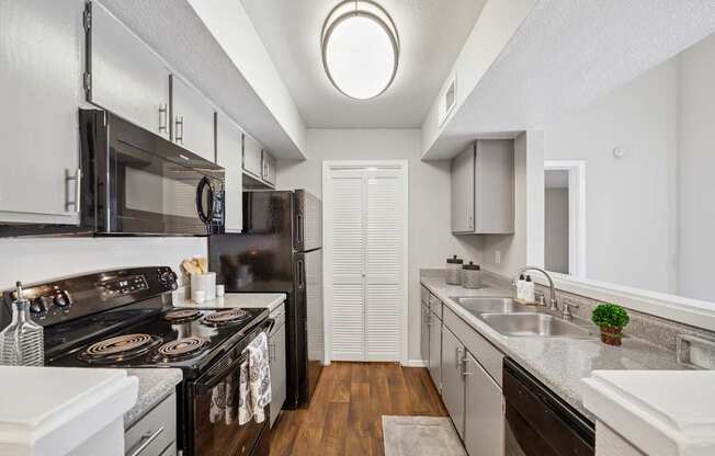 A modern kitchen with black appliances and white cabinets.