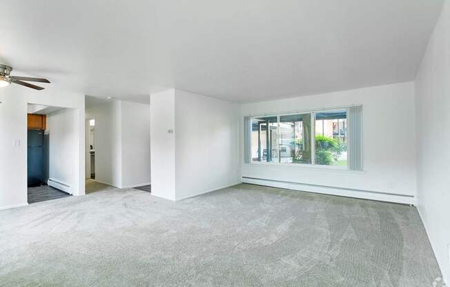 an empty living room with a large window and white walls