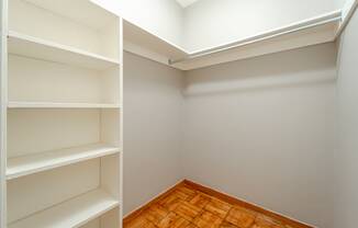 a walk in closet in a home with gray walls and a wooden floor