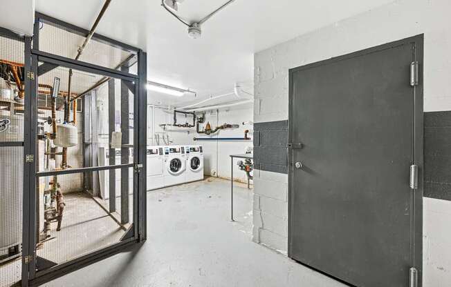 A large black door is open to a room with a washing machine and other appliances.