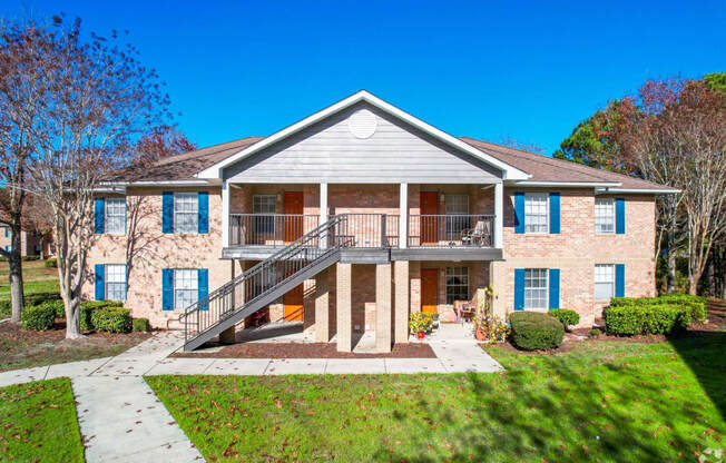 the front of a brick house with a balcony and a staircase