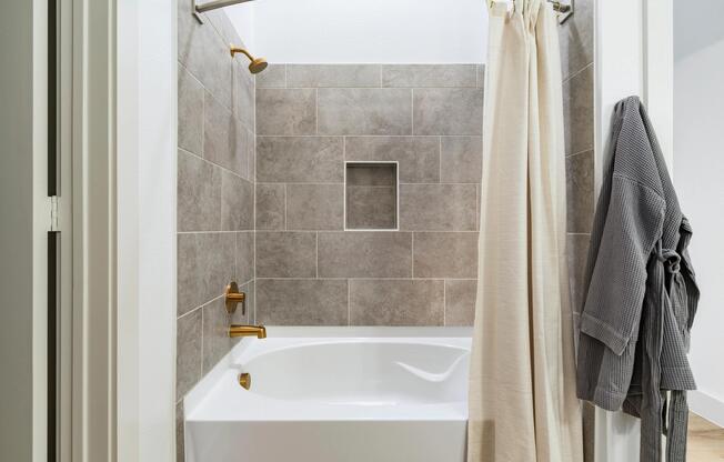Primary bath with a tiled tub and shower surround, built-in niche, and warm-toned finishes designed for everyday comfort.